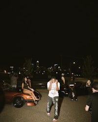 a group of people standing in front of a car at night